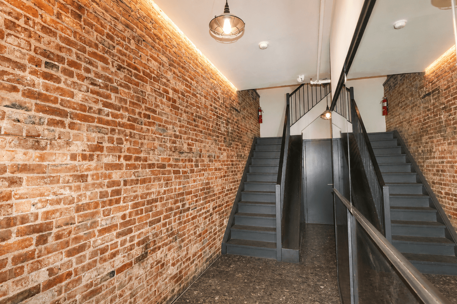 A staircase with a metal railing and steps leading up to a door.